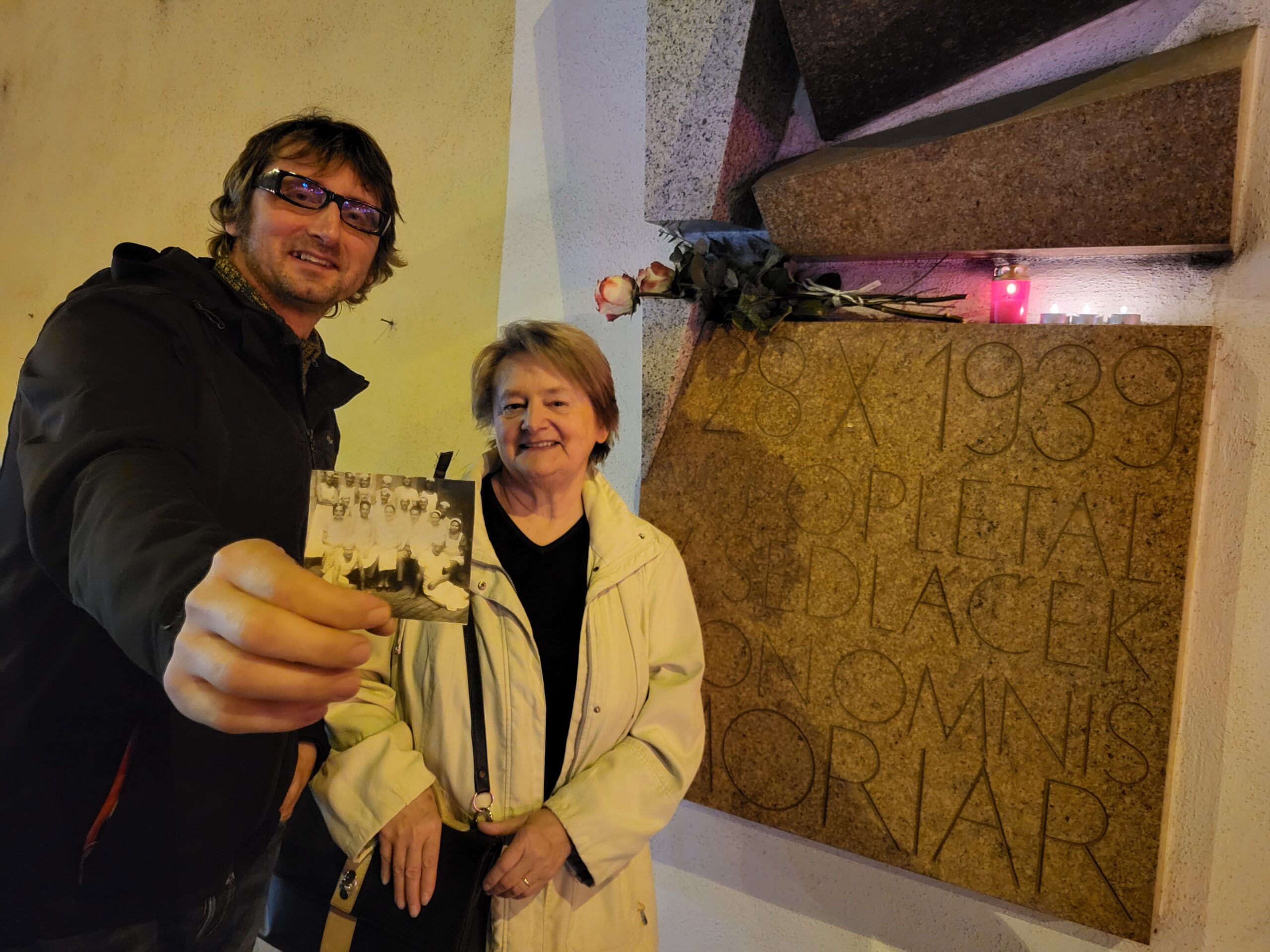 Milada Zikmundová a Martin Krsek u památníku Jana Opletala a Václava Sedláčka v pražské Žitné ulici. Martin Krsek drží fotografii personálu někdejší pekárny Ladislava Vrbického