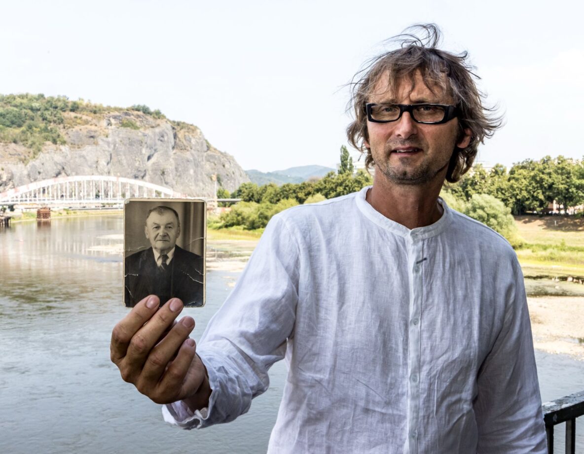 Martin Krsek s fotografií svého prapradědy Josefa Schneidera z Olšinek, v pozadí Benešův most